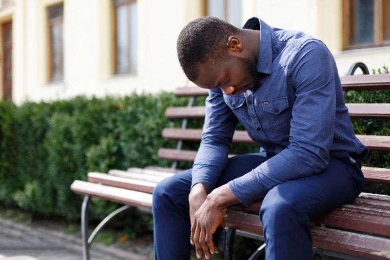 disappointed man sitting on a bench with head down