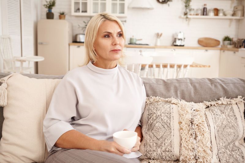 woman sitting alone with a cup of tea in her living room