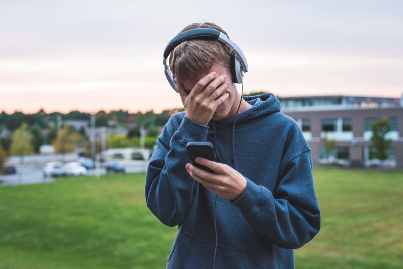 disappointed teenager outside listening to music on phone