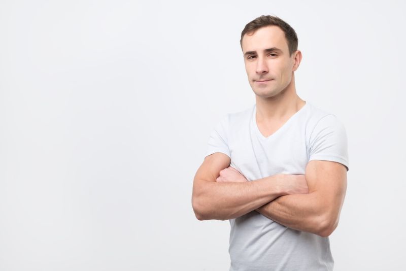 Confident man in white tee shirt standing with arms crossed