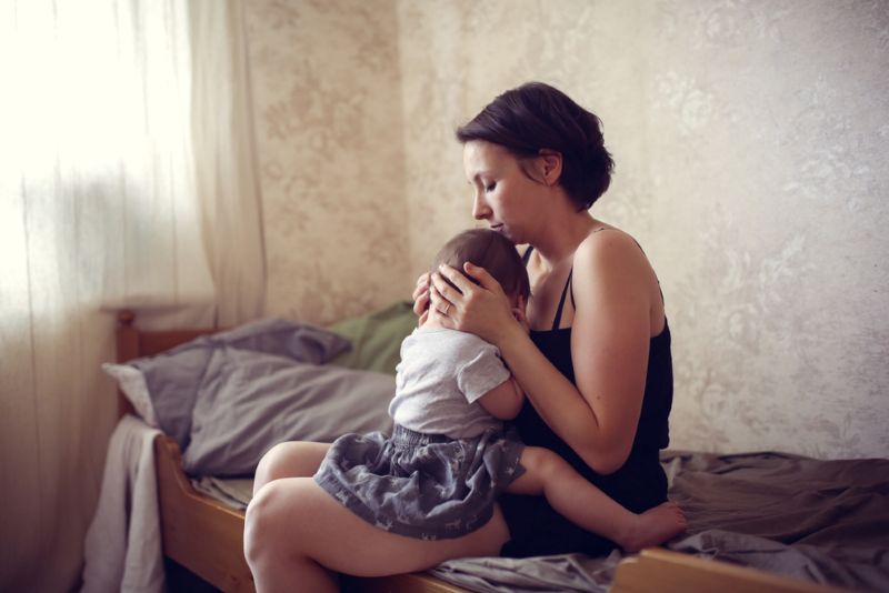 Mother sitting on bed with newborn child